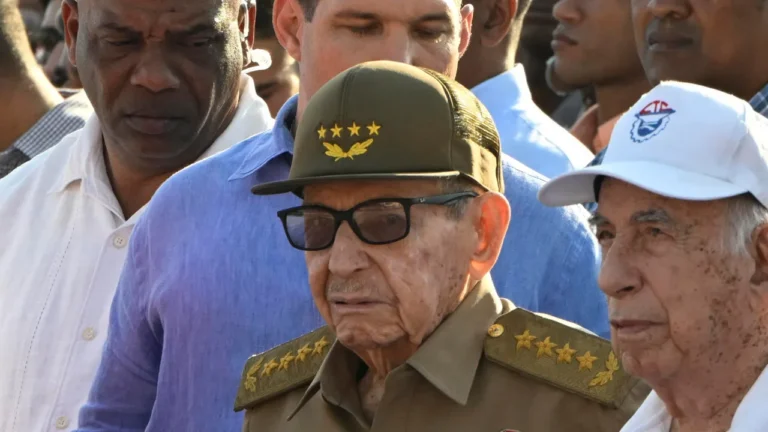Estados Unidos evalúa acusar a Raúl Castro mientras aumenta la presión de Trump sobre Cuba An elderly man in military attire, featuring a cap with stars and glasses, stands amidst a group of people.