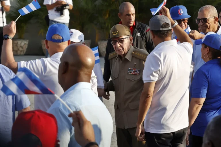 Raúl Castro y Estados Unidos: una relación atrapada entre el miedo y la conveniencia Group of people waving Cuban flags and greeting a military officer in uniform outdoors.